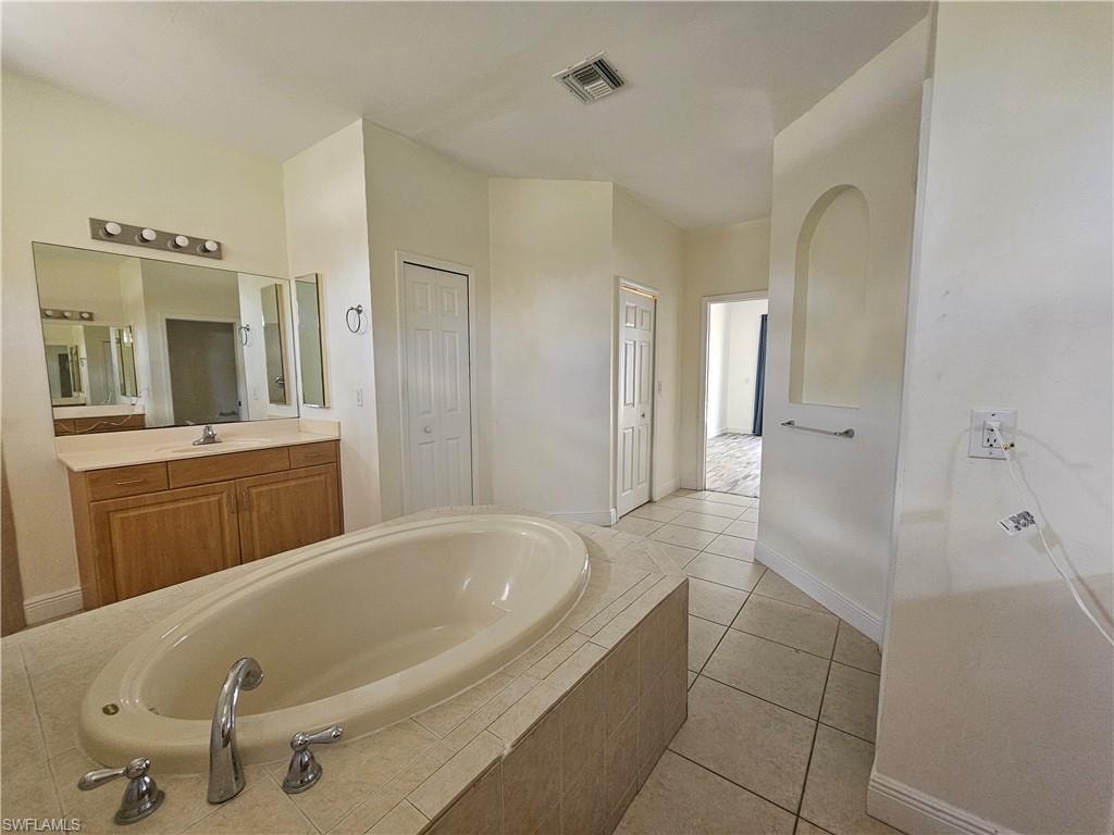 Tiled flooring, sliding glass doors, tray ceiling, kitchen island with built-in sink, and dark wood cabinetry
