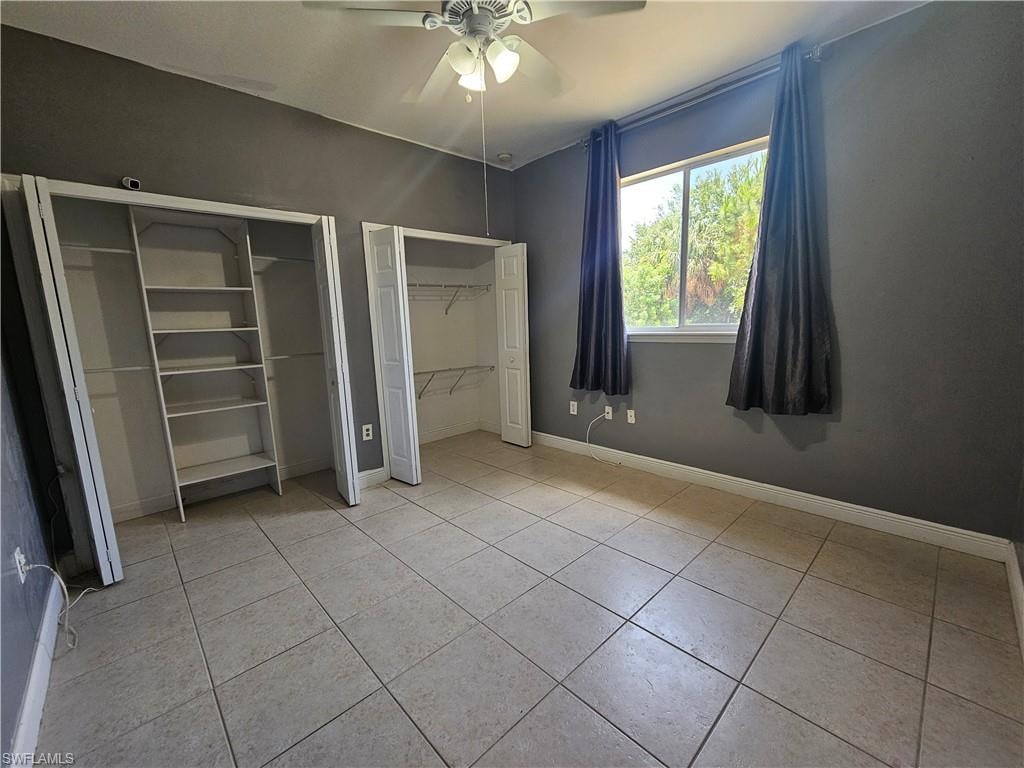 Tiled flooring with bi-fold closet doors, a window, and a ceiling fan with integrated lighting