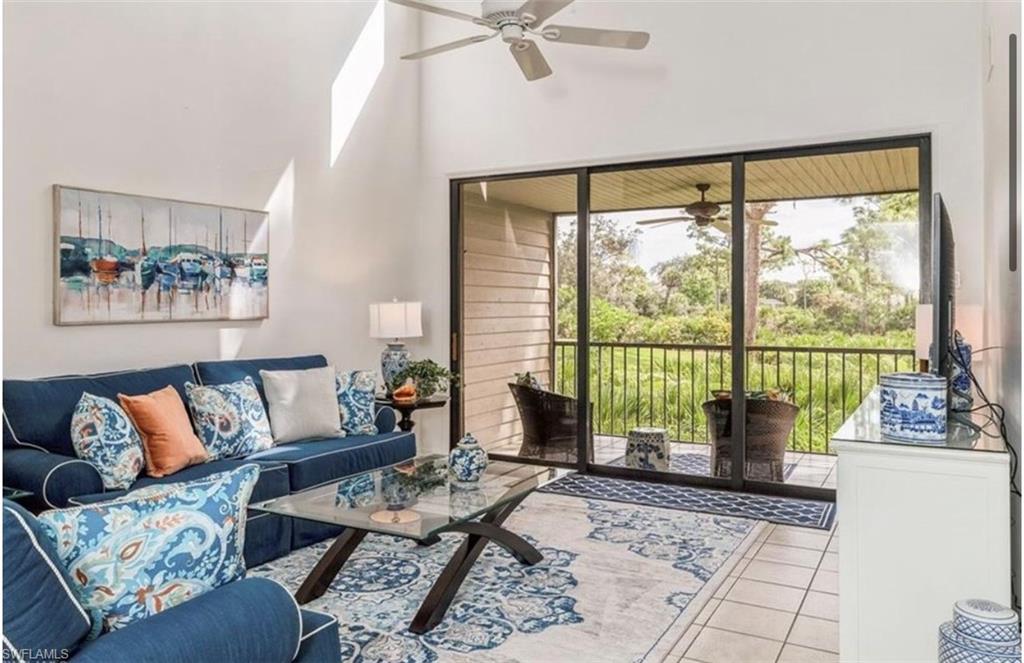 Tiled living area with plenty of natural light, a ceiling fan, and a high ceiling