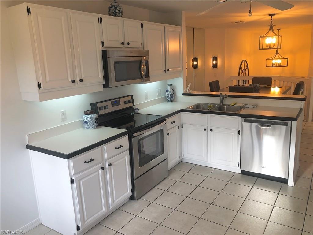 Kitchen featuring stainless steel appliances, a peninsula, white cabinetry, and dark countertops