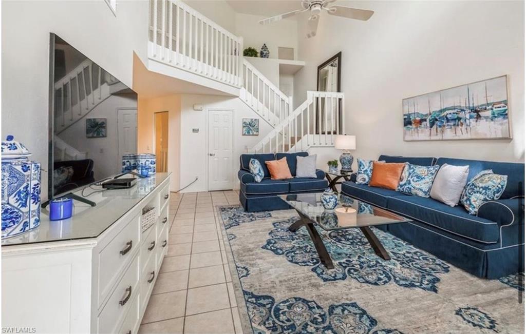 Living area featuring a high ceiling, light tile patterned floors, and ceiling fan