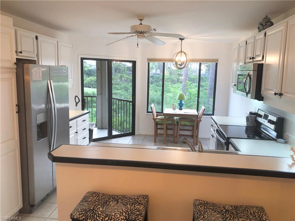 Kitchen featuring light tile patterned flooring, stainless steel appliances, white cabinetry, and a ceiling fan