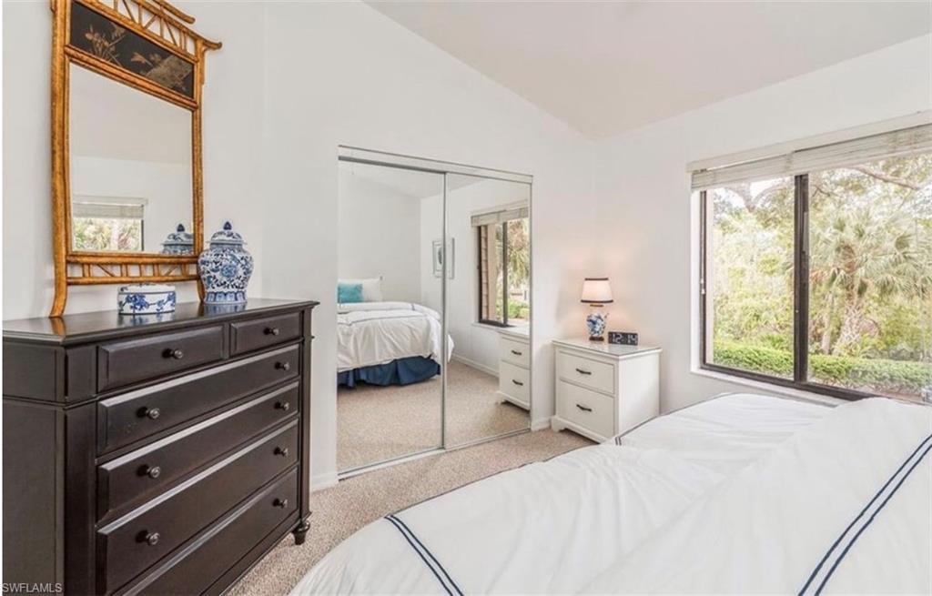 Bedroom featuring vaulted ceiling, light carpet, a closet, and multiple windows