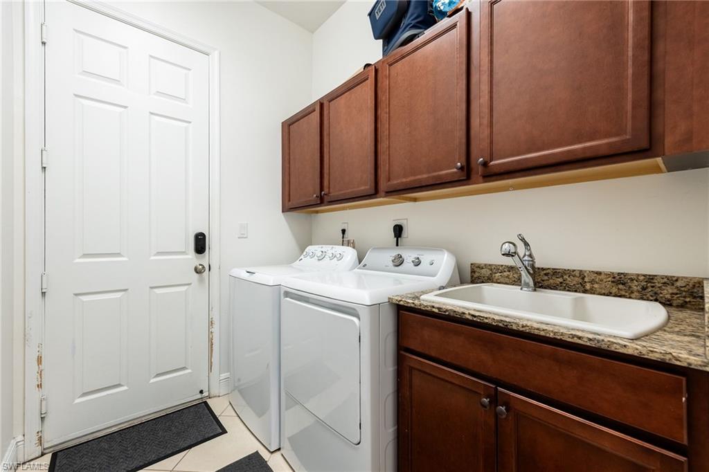 Laundry area featuring separate washer and dryer, cabinet space, and light tile patterned flooring