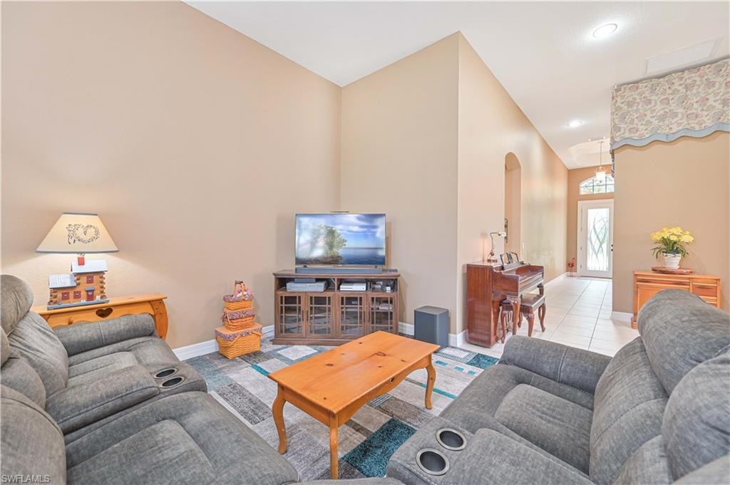 Living room featuring arched walkways, tile patterned floors, and recessed lighting