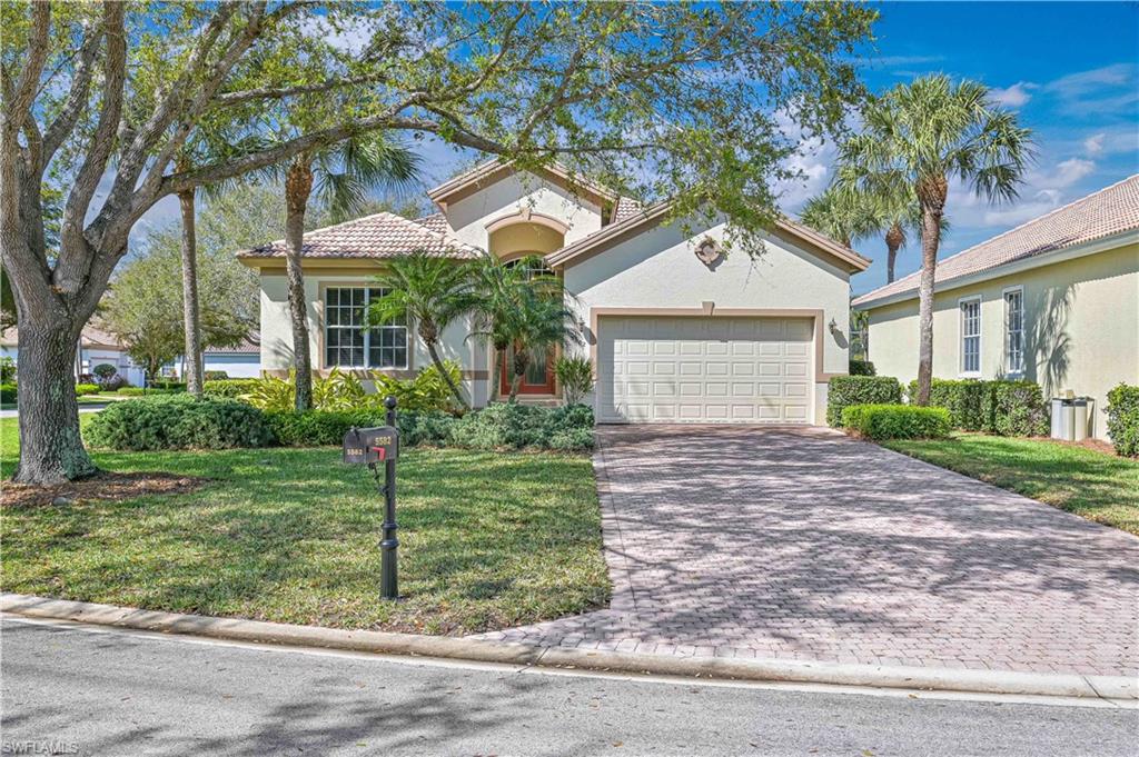 Mediterranean / spanish-style house featuring an attached garage, decorative driveway, a front lawn, stucco siding, and a tiled roof