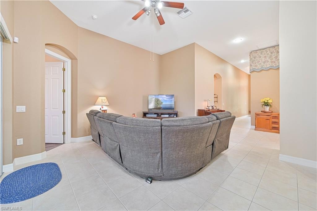 Living area with arched walkways, light tile patterned floors, a ceiling fan, and recessed lighting