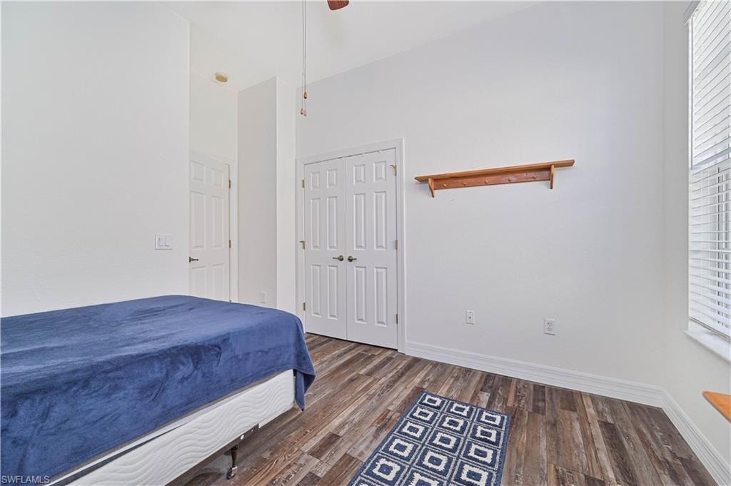Bedroom with a ceiling fan, dark wood-type flooring, a closet, and a high ceiling