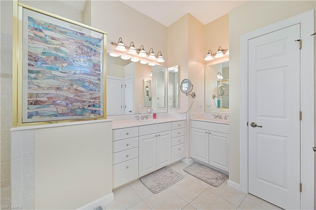 Full bathroom with two vanities and light tile patterned floors