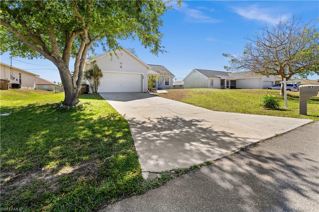 Single story home featuring a garage, a front lawn, driveway, stucco siding, and a residential view