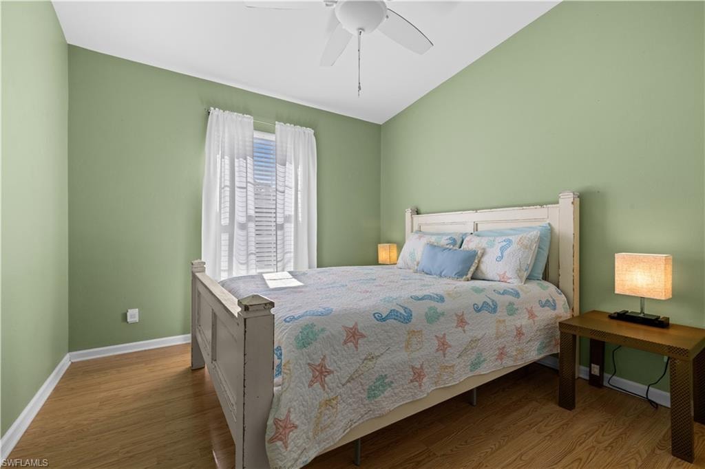 Bedroom with light wood finished floors, a ceiling fan, and vaulted ceiling