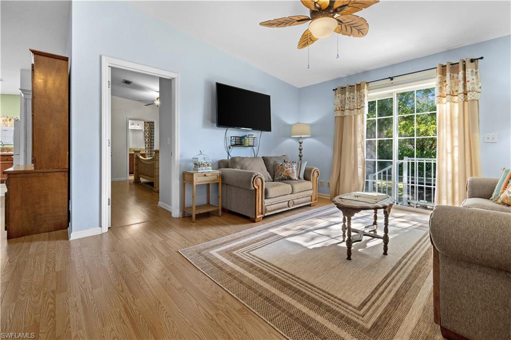 Living area featuring a ceiling fan, lofted ceiling, and light wood-type flooring