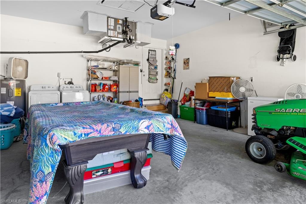 Garage featuring water heater, washer and dryer, and a garage door opener