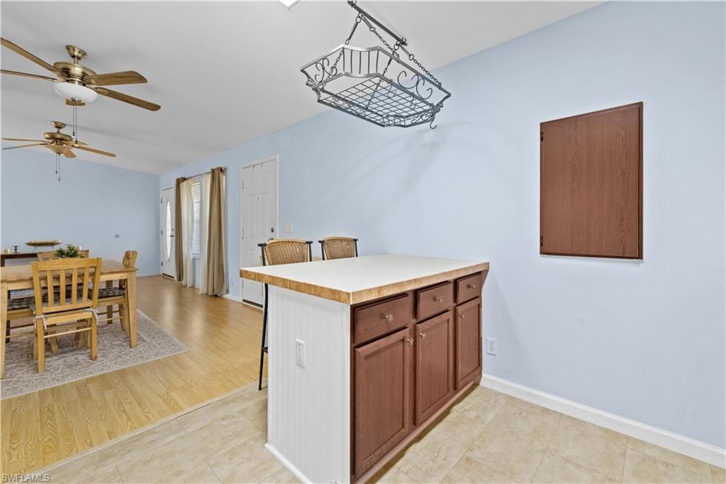 Kitchen with light countertops, a peninsula, ceiling fan, wood finish cabinets, and a breakfast bar area