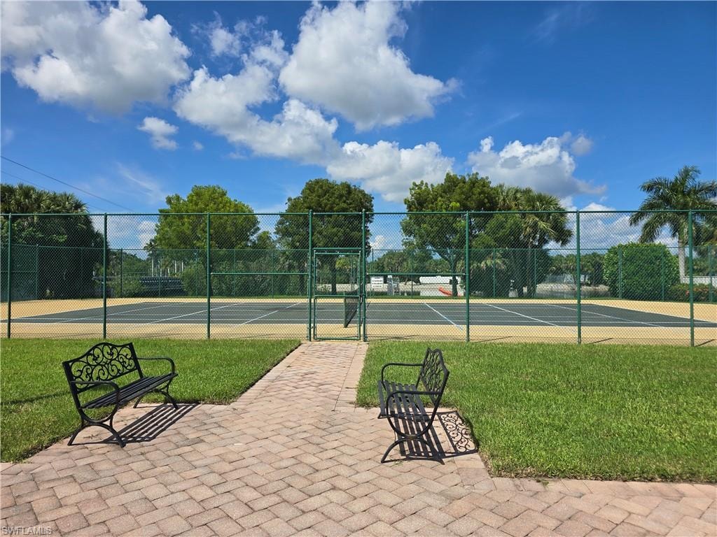 View of community tennis court and a gate
