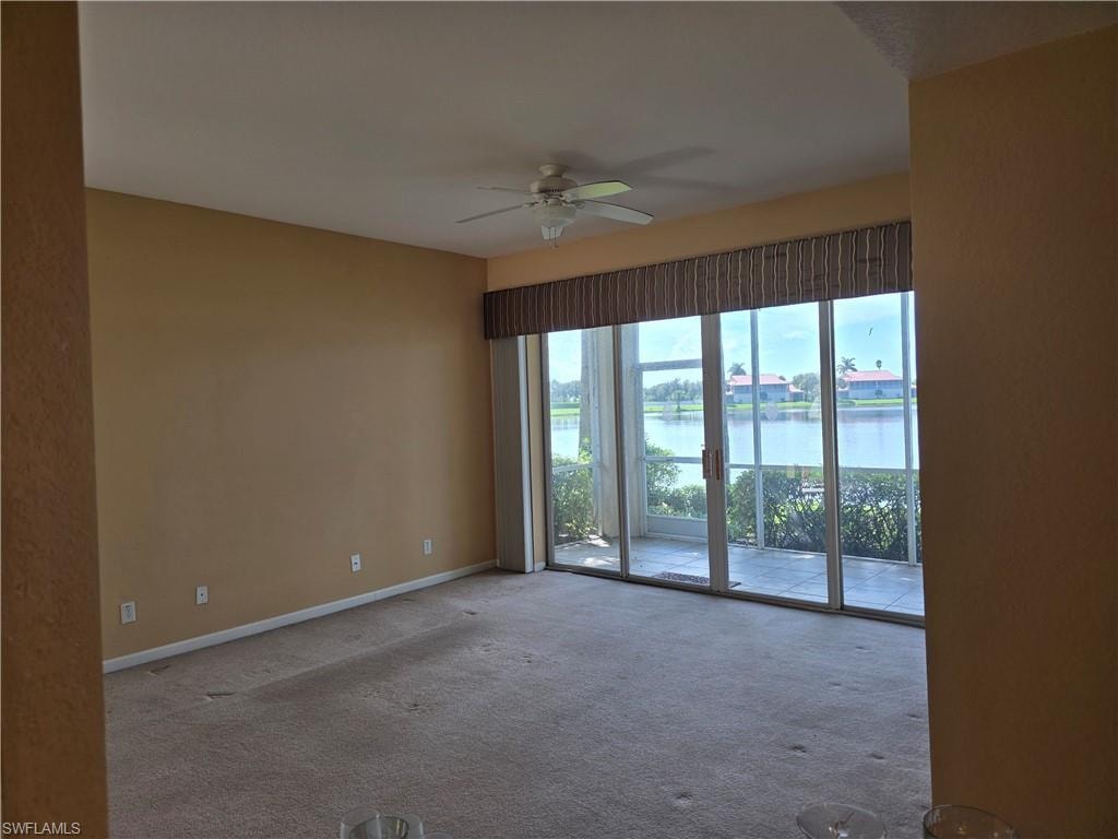 Carpeted living room with ceiling fan and a lake view