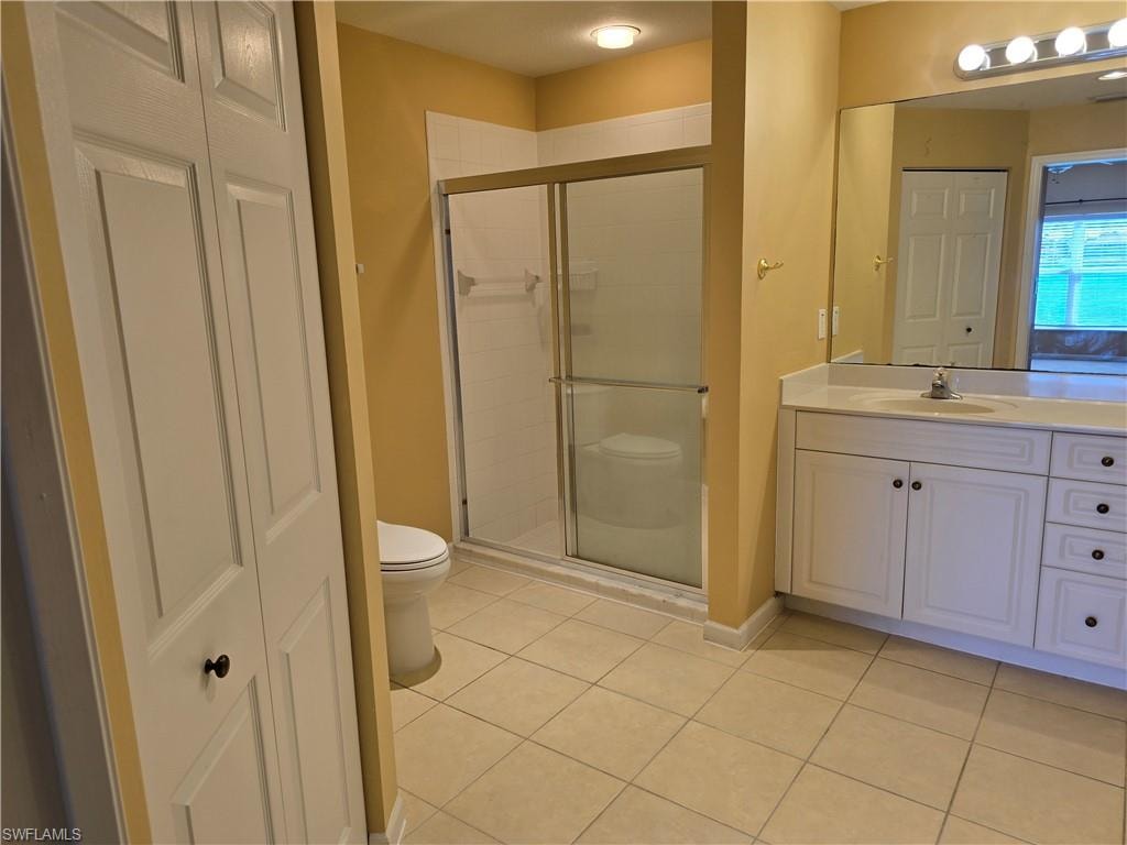 Master bathroom with a closet, light tile patterned flooring, and vanity