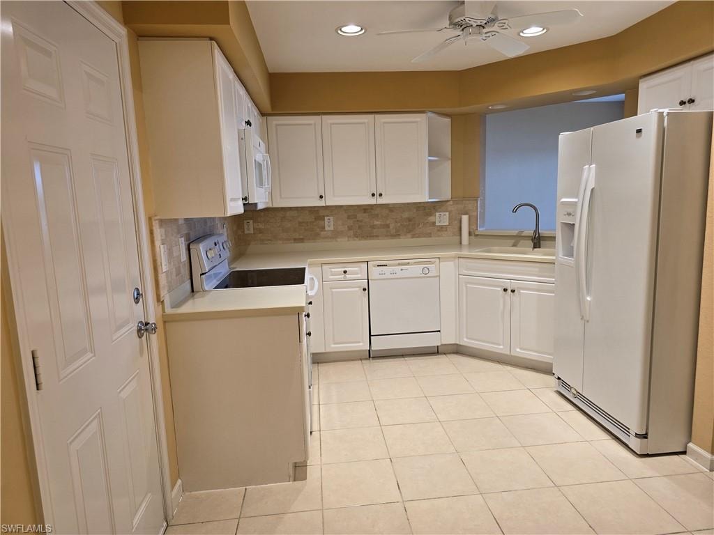 Kitchen featuring white appliances, light countertops, a ceiling fan, white cabinetry, and recessed lighting
