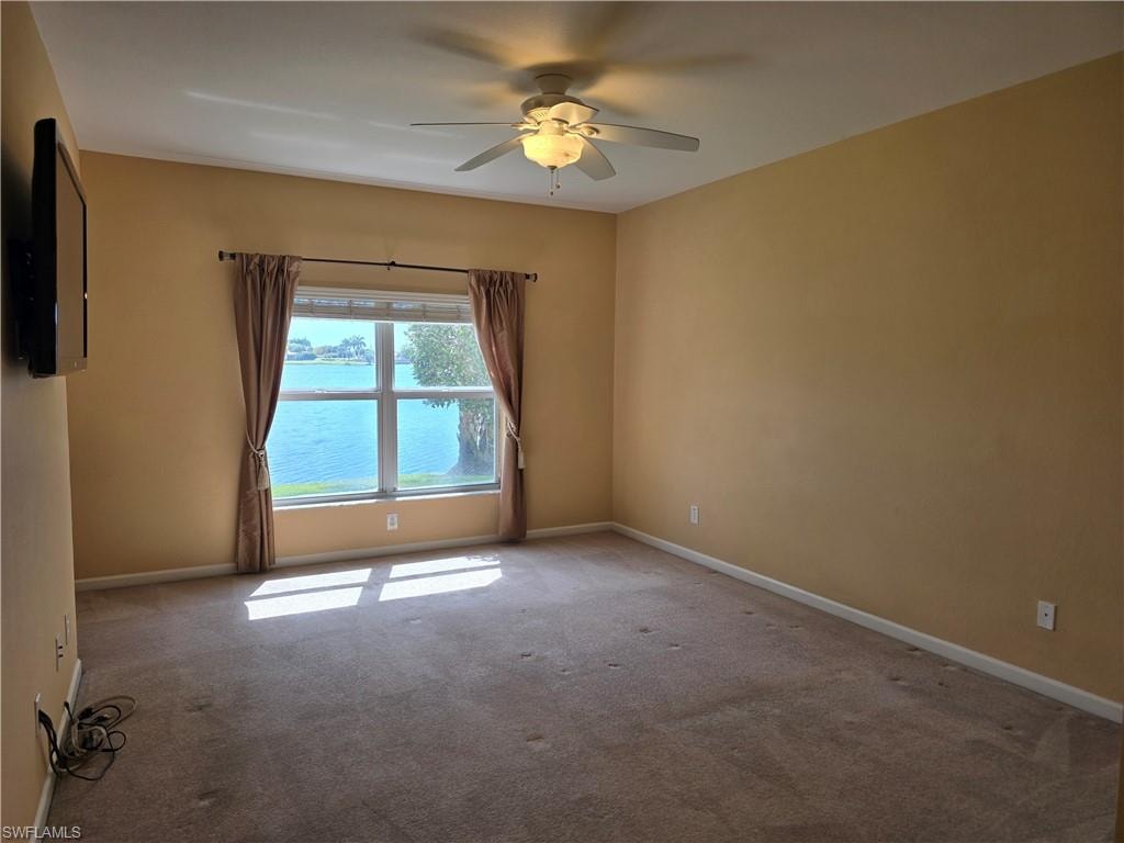 Master bedroom with a ceiling fan and carpet floors and view of lake