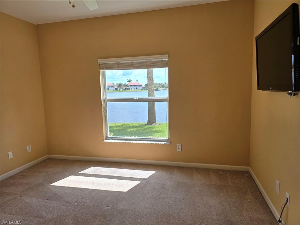 Carpeted 2nd bedroom room with baseboards and ceiling fan and view of lake