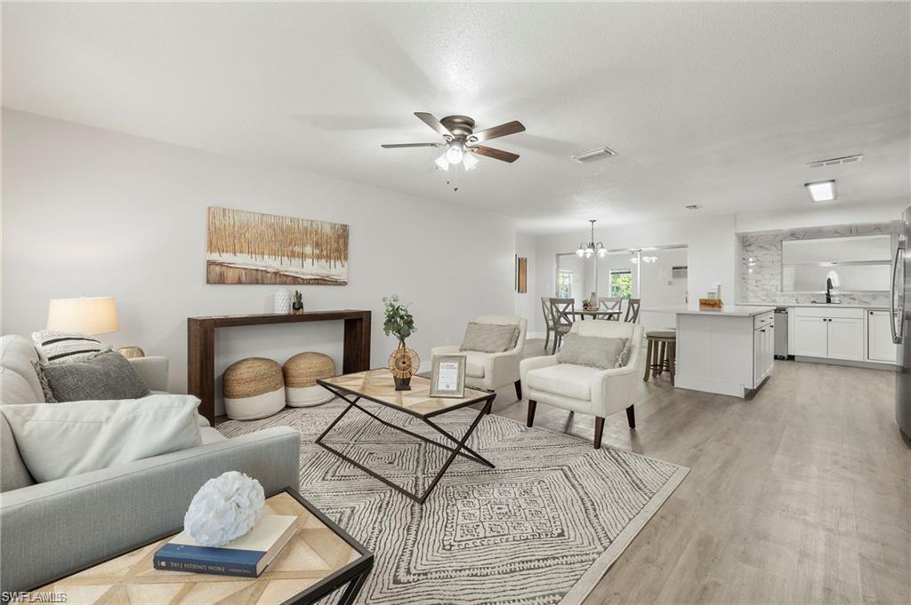 Living room featuring a ceiling fan, light wood-style flooring, and a chandelier
