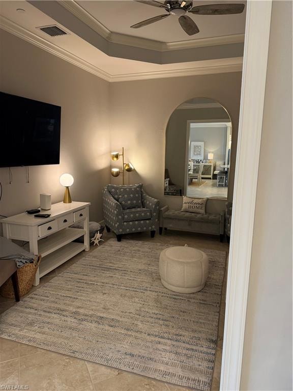 Tiled living room with ceiling fan, crown molding, and a tray ceiling