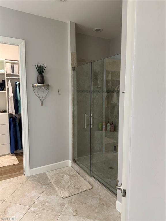 Full bathroom featuring a stall shower, a spacious closet, and light tile patterned flooring