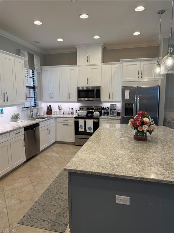Kitchen featuring stainless steel appliances, ornamental molding, light stone countertops, white cabinetry, and pendant lighting