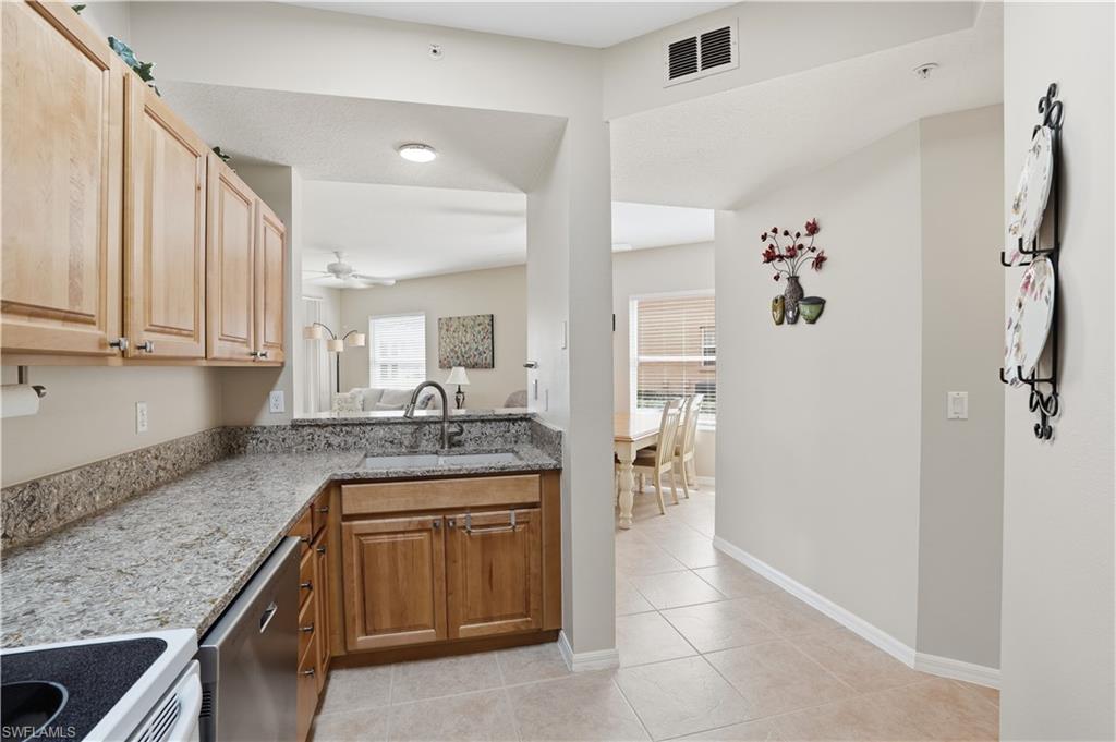 Kitchen featuring electric range, light stone countertops, dishwasher, light tile patterned floors, and a ceiling fan