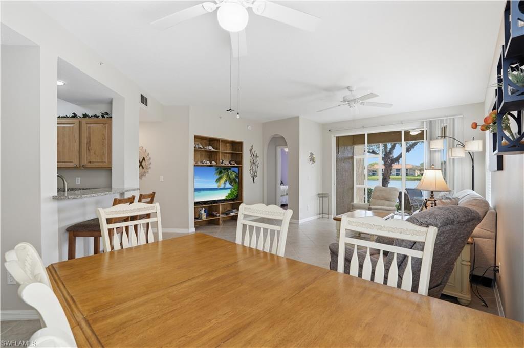 Dining area featuring arched walkways, light tile patterned floors, and a ceiling fan