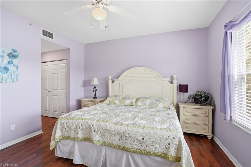 Bedroom with a closet, a ceiling fan, dark wood-style flooring, and multiple windows
