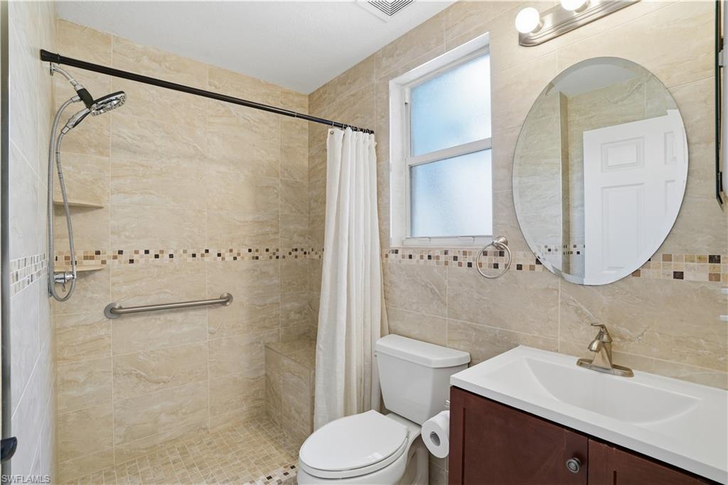 Bathroom featuring vanity, a stall shower, and tile walls