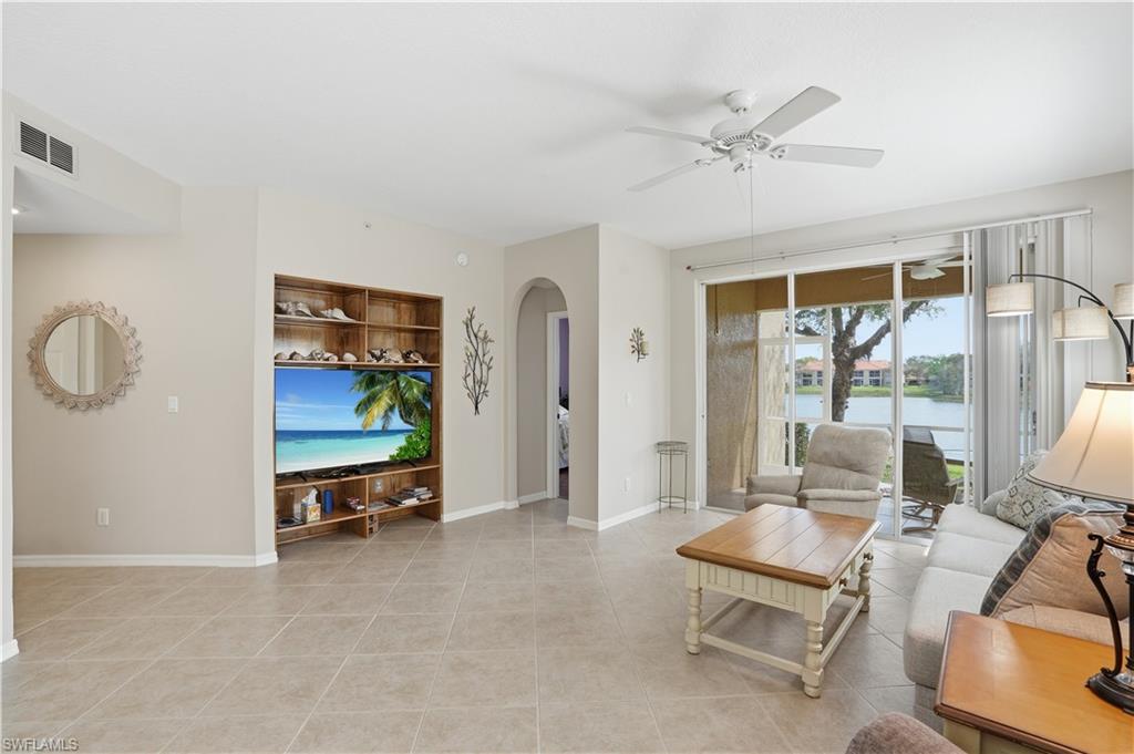 Living room featuring arched walkways, ceiling fan, and light tile patterned floors