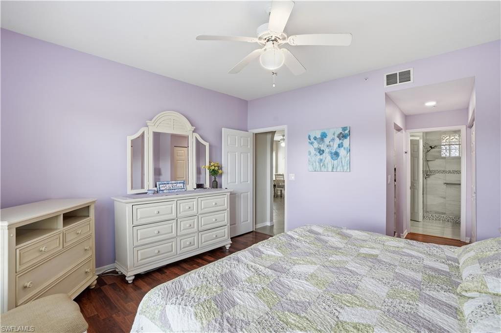 Bedroom with dark wood-style floors, ceiling fan, and connected bathroom