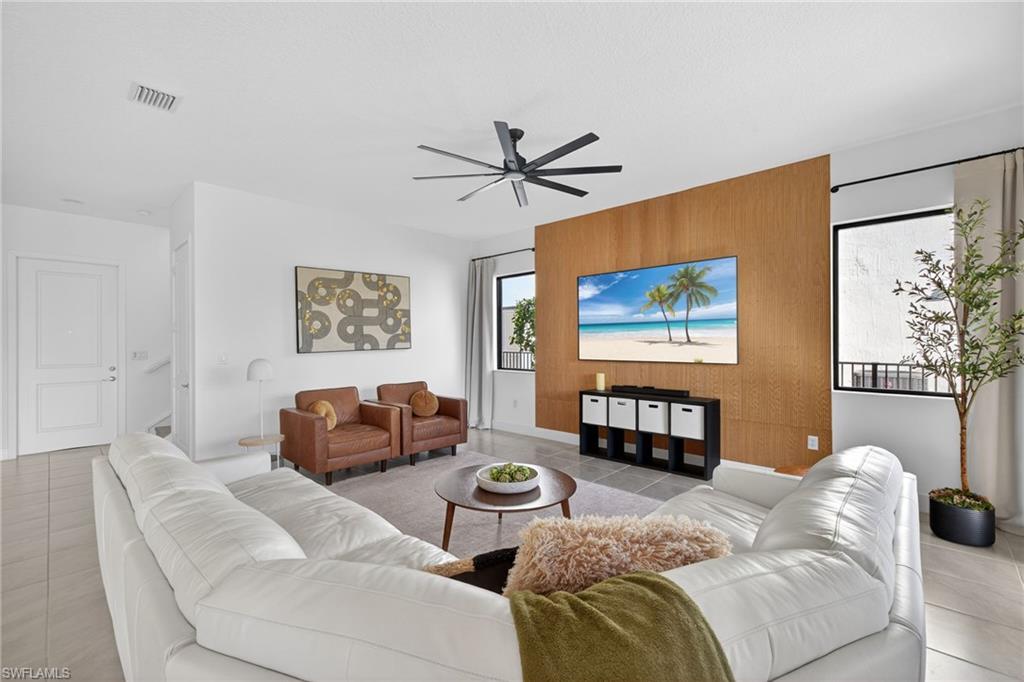 Living area featuring an accent wall, light tile patterned floors, ceiling fan, and wood walls