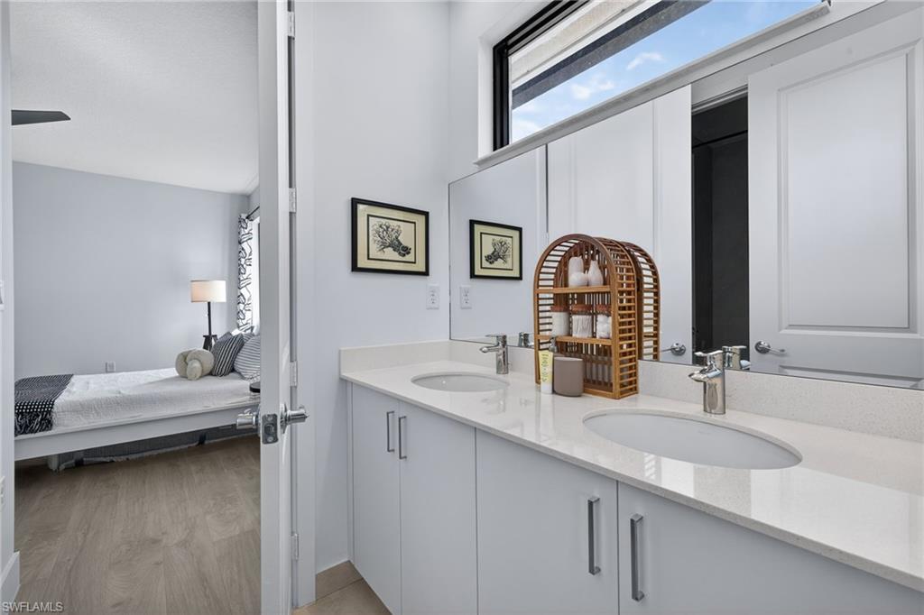 Bathroom featuring ensuite bathroom, double vanity, and light wood-type flooring