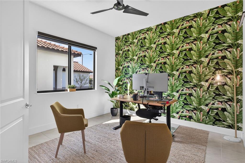 Office with wallpapered walls, an accent wall, a ceiling fan, and light tile patterned floors