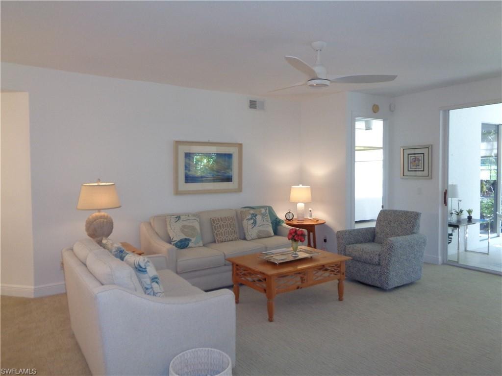 Living area featuring light colored carpet and ceiling fan