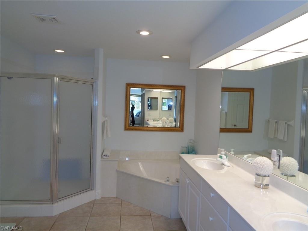 Bathroom with double vanity, a shower stall, a bath, light tile patterned floors, and recessed lighting