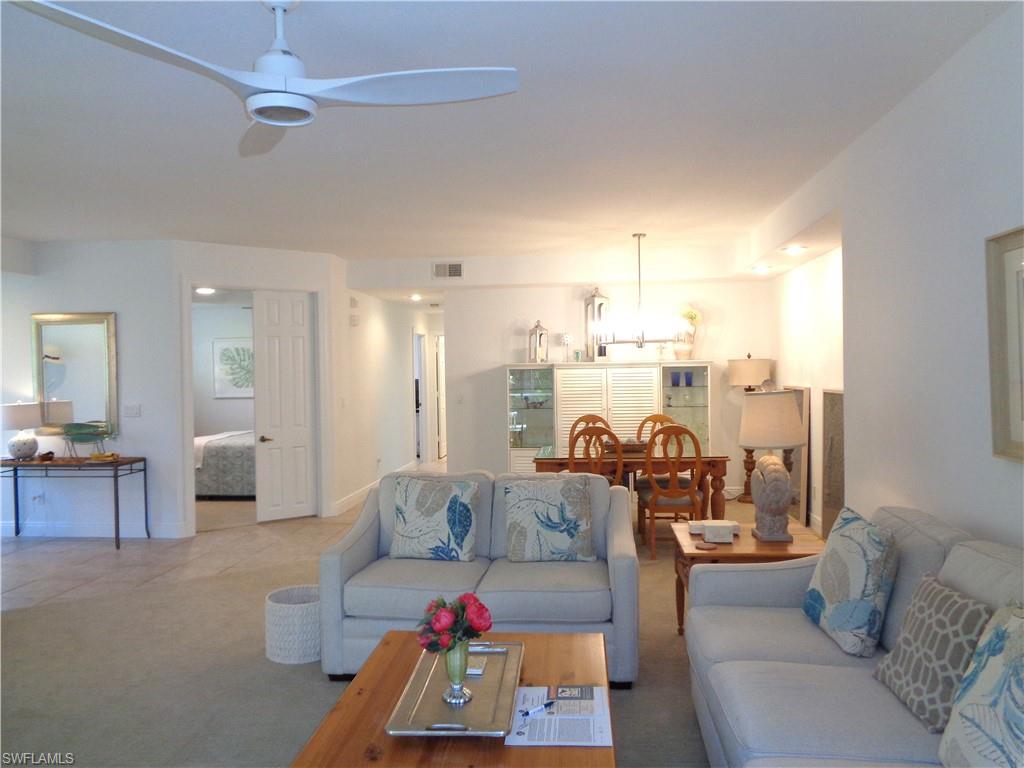 Carpeted living area featuring suspended lighting and a ceiling fan