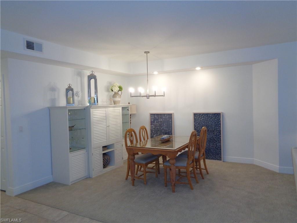 Dining room with hanging lights and light colored carpet