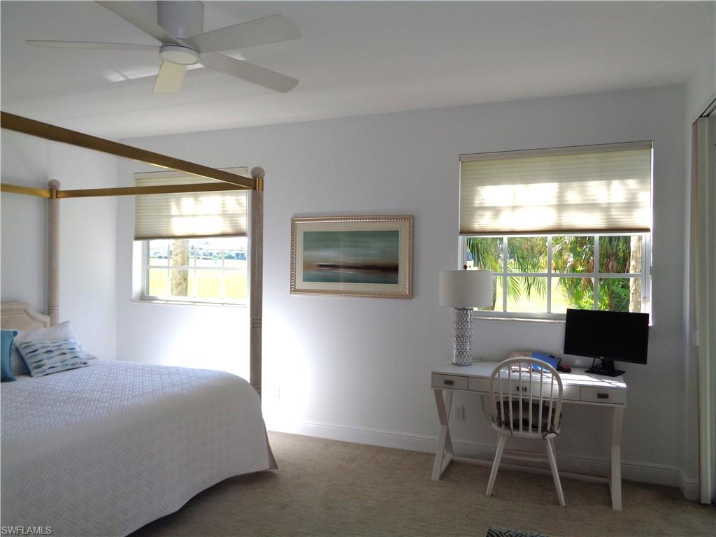 Bedroom with light colored carpet, multiple windows, and ceiling fan