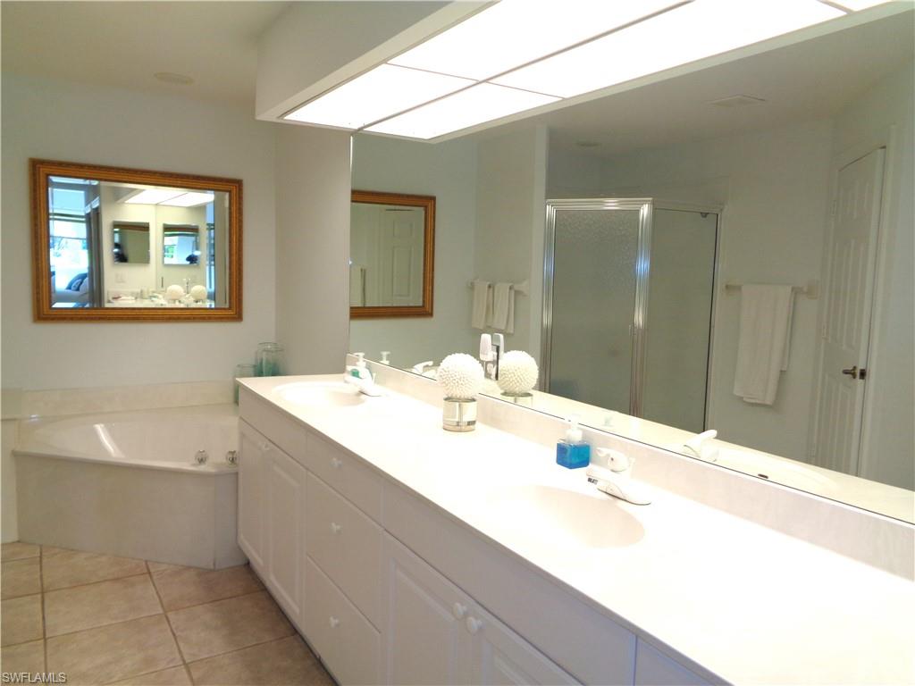 Bathroom featuring double vanity, a stall shower, a bath, and light tile patterned floors