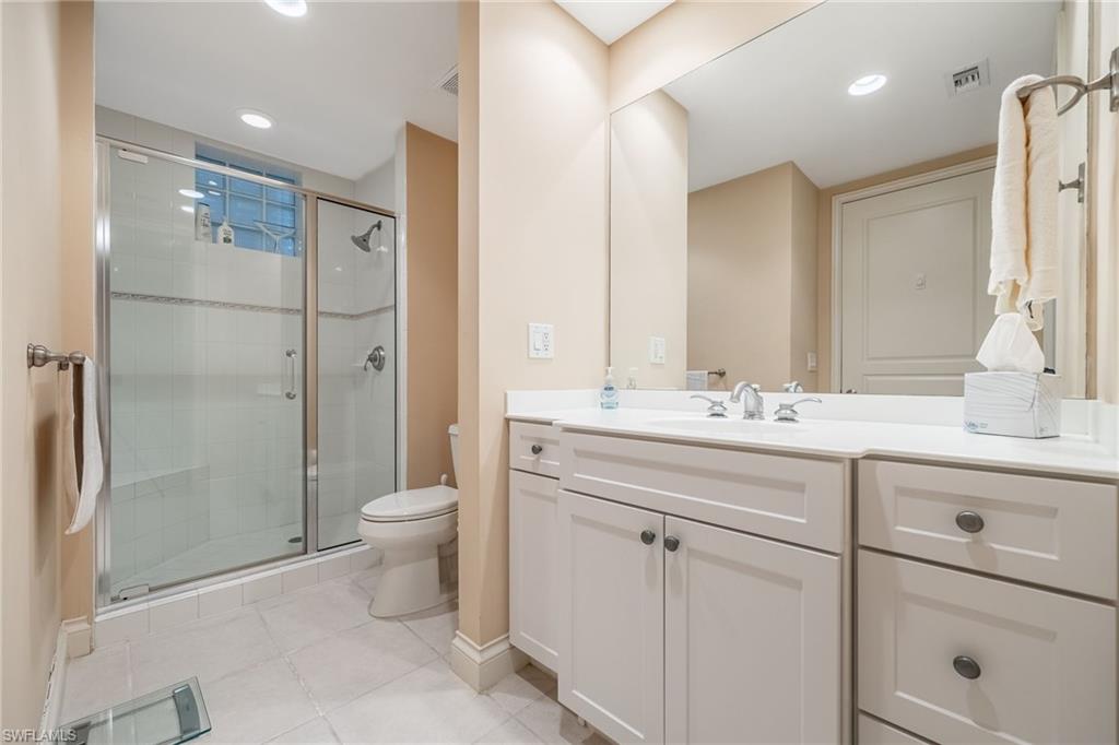 Bathroom featuring vanity, a shower stall, light tile patterned flooring, and recessed lighting