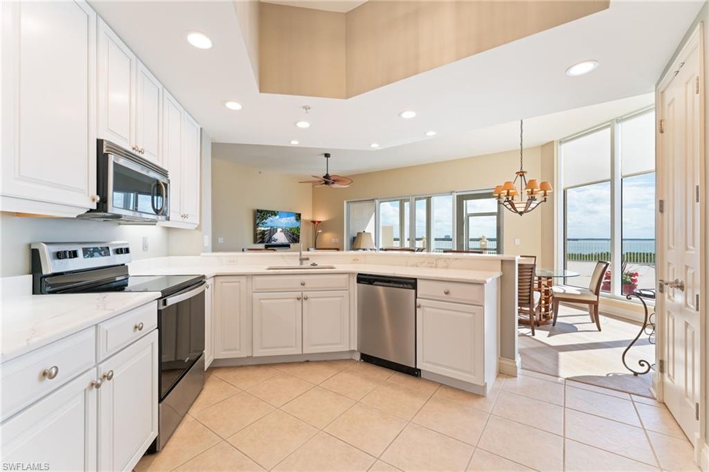 Kitchen with stainless steel appliances, white cabinets, a peninsula, and hanging lights