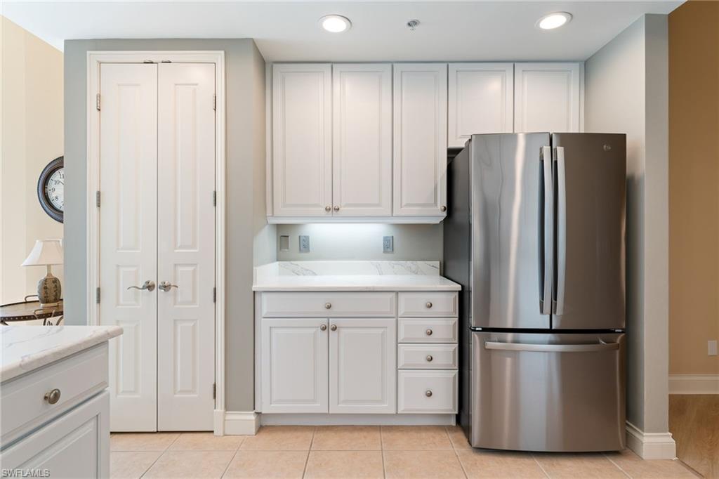Kitchen featuring freestanding refrigerator, white cabinetry, light stone counters, and recessed lighting