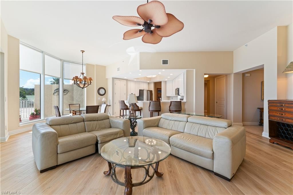 Living room featuring light wood-style flooring, a ceiling fan, and suspended lighting