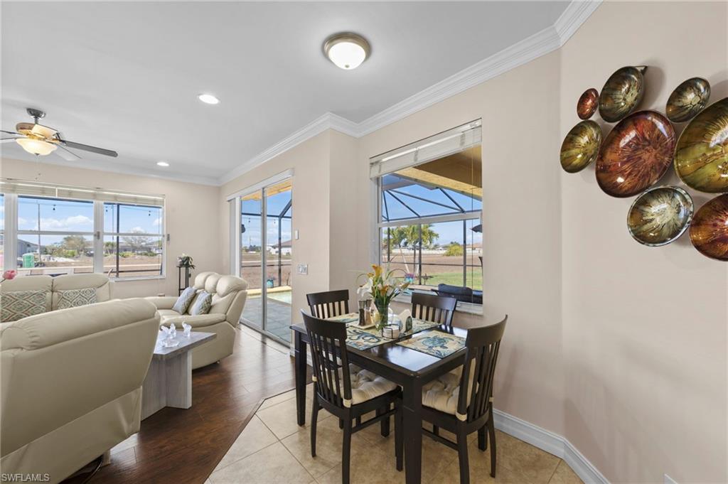 Dining space featuring a sunroom, a ceiling fan, crown molding, plenty of natural light, and light wood-style flooring
