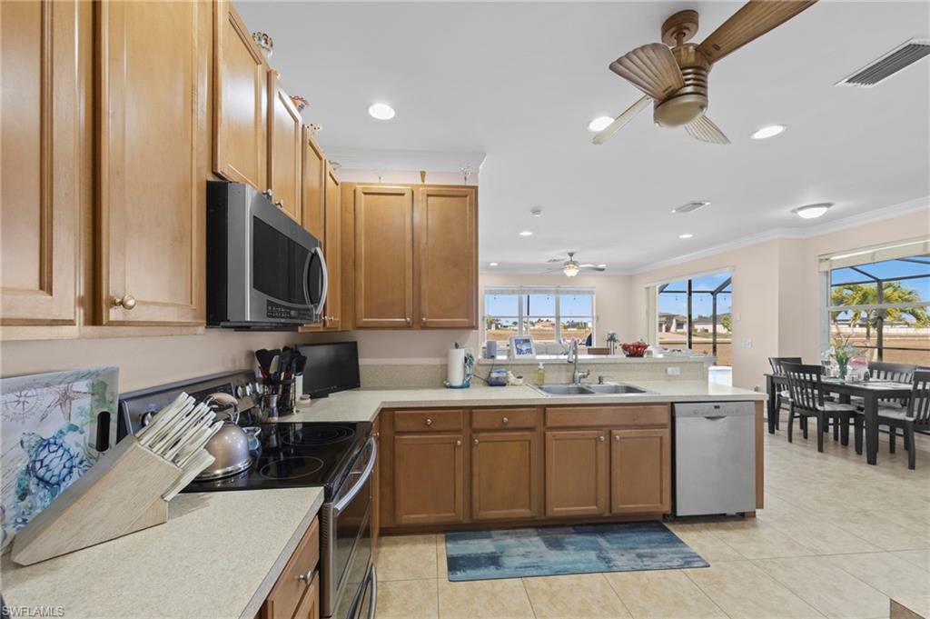 Kitchen featuring stainless steel appliances, light countertops, a peninsula, recessed lighting, and light tile patterned flooring
