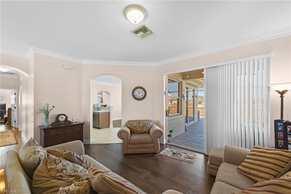 Living room with hardwood / wood-style floors, arched walkways, and ornamental molding